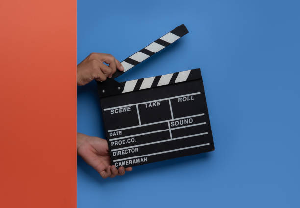 istock Hand is holding clapper board or clapperboard or movie slate on blue background. 1589879893