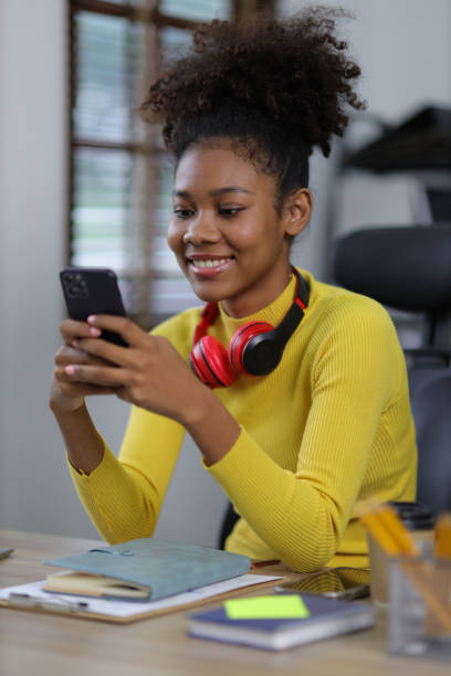 istock Young beautiful african woman in home office using smartphone and calling with someone. 1589889162