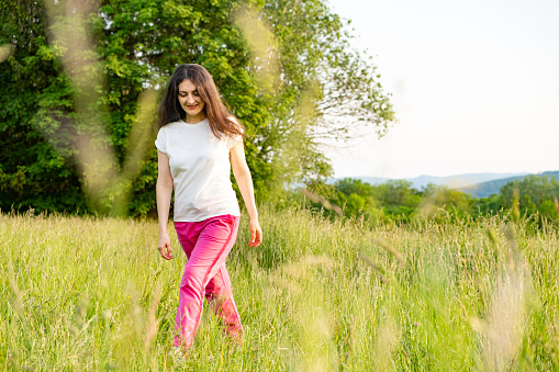 A young woman walks across a field. A walk in nature in the summer