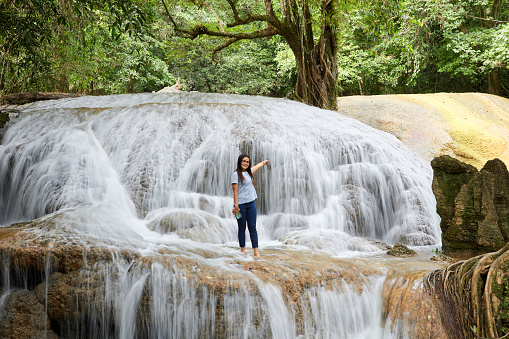 Woman standing amidst waterfall in forest