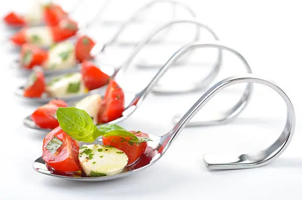 Tomato, mozzarella, basil and olive oil with herbs (Caprese) on a spoon