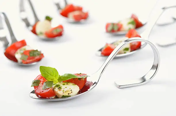 Tomato, mozzarella, basil and olive oil with herbs on a spoon