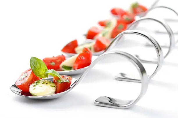 Tomato, mozzarella, basil and olive oil with herbs on a spoon