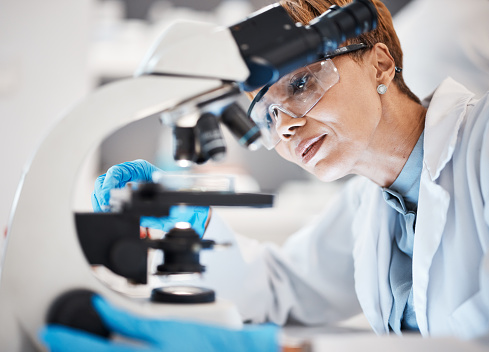 Medical science, woman and microscope in a laboratory for research, analytics and to study particle. Scientist person with glasses for dna or bacteria in lab for innovation, future and biotechnology