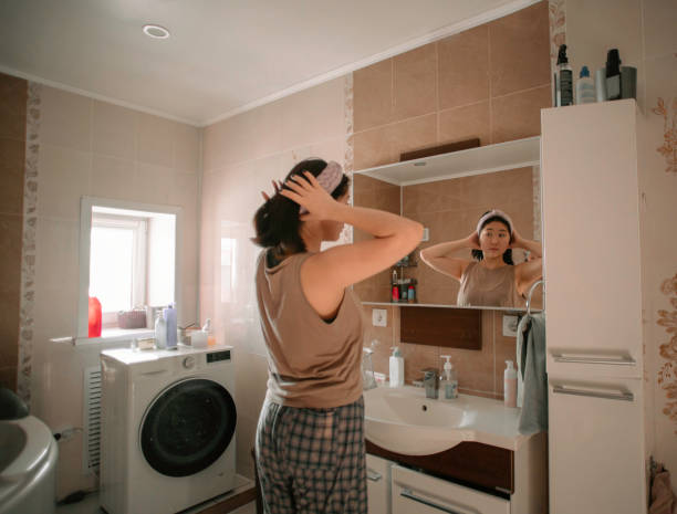 Asian beauty starts her morning routine with a reflection in the bathroom mirror stock photo