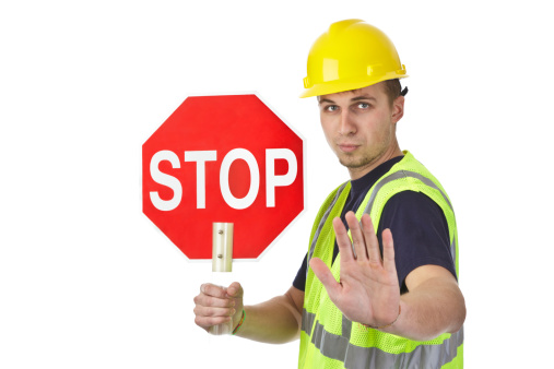A construction worker holds up a stop sign.