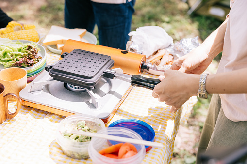 Close up shot of Japanese mother preparing food for her family, while camping in nature together.