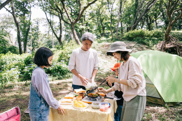 famille japonaise préparant le déjeuner au camping dans la nature - camping family tent couple photos et images de collection