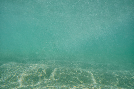 Under the sea surface after a wave has passed at Pedn Vounder Beach, South Cornwall on a sunny June day.