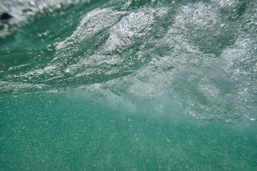 Under the sea surface after a wave has passed at Pedn Vounder Beach, South Cornwall on a sunny June day.