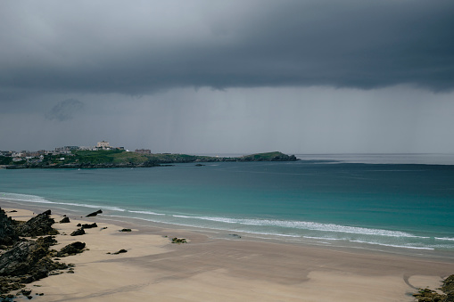 Low storm clouds with distant heavy rain over the sea at Newquay, Cornwall on a bad weather June day.
