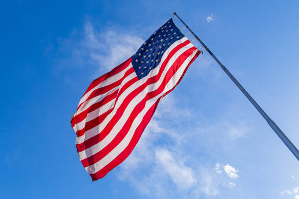 istock USA flag on clear blue sky. 1589950791