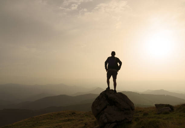 istock silhouette of a man on a rock at sunset 1589957573
