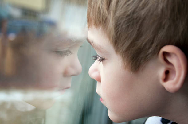 istock Reflection of a small boy as he looks out the window 158996290