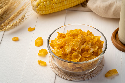 Healthy crispy cornflakes in glass bowl on wood table