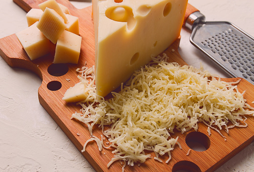Grated cheese, Maasdam, on a cutting board, grater and cheese knife, close-up, no people,
