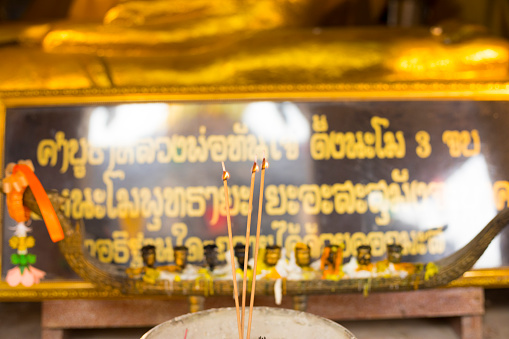 Burning thai incense sticks in front of buddha statue  below which is some text at Wat Doi Thaen Phra Pha Luang in San Sai  district of Chiang Mai
