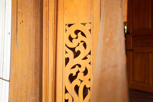 Wood sculpture in Thai style located at the window of traditional Thai house.