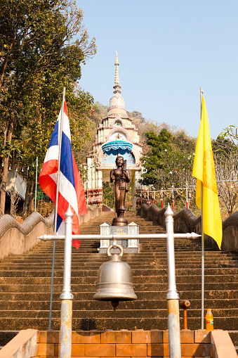 Bells and buddha statue under umbrella on steps  at Wat Doi Thaen Phra Pha Luang in San Sai  district of Chiang Mai