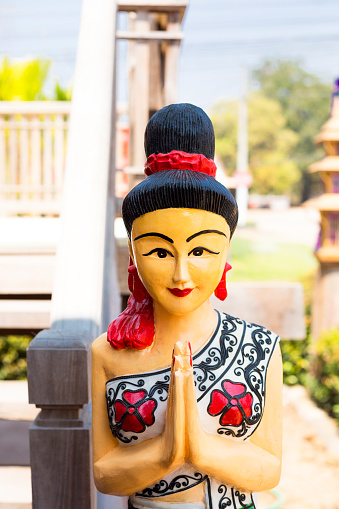 Wooden female thai statue with Wai gesture welcoming people at cultural old house in On Tai, Chiang Mai, San Kamphaeng district of Chiang Mai