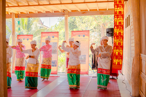 Group of mature thai women in northern traditional fashion are dancing at cultural old house in On Tai, Chiang Mai, San Kamphaeng district of Chiang Mai. Women are performing tradition  and arts which are are common in area of On Tai. District is center of northern traditional thai art and craft and history. Women are dancing below a well restored classical wooden stilt house.