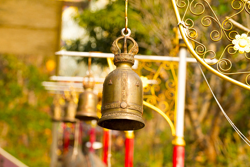 Picture of a golden copper bell hanging on the wall of church area
