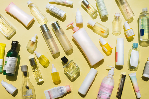 Beauty products, cosmetics products, perfume products, body care products, baby care products, and essential oil bottles on yellow background, all is empty bottles for being recycled. Recycling, reuse, and sustainability of beauty and cosmetic products