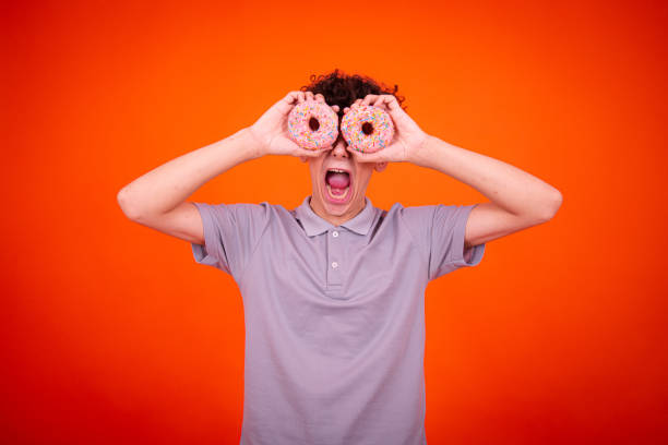 istock Young attractive guy eats pink donuts. Delicious breakfast and good vibes. 1590004442