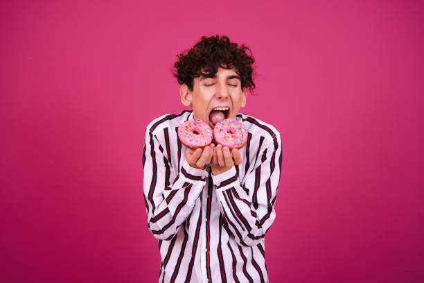 istock Young attractive guy eats pink donuts. Delicious breakfast and good vibes. 1590011776
