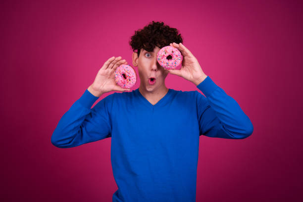 istock Young attractive guy eats pink donuts. Delicious breakfast and good vibes. 1590038654