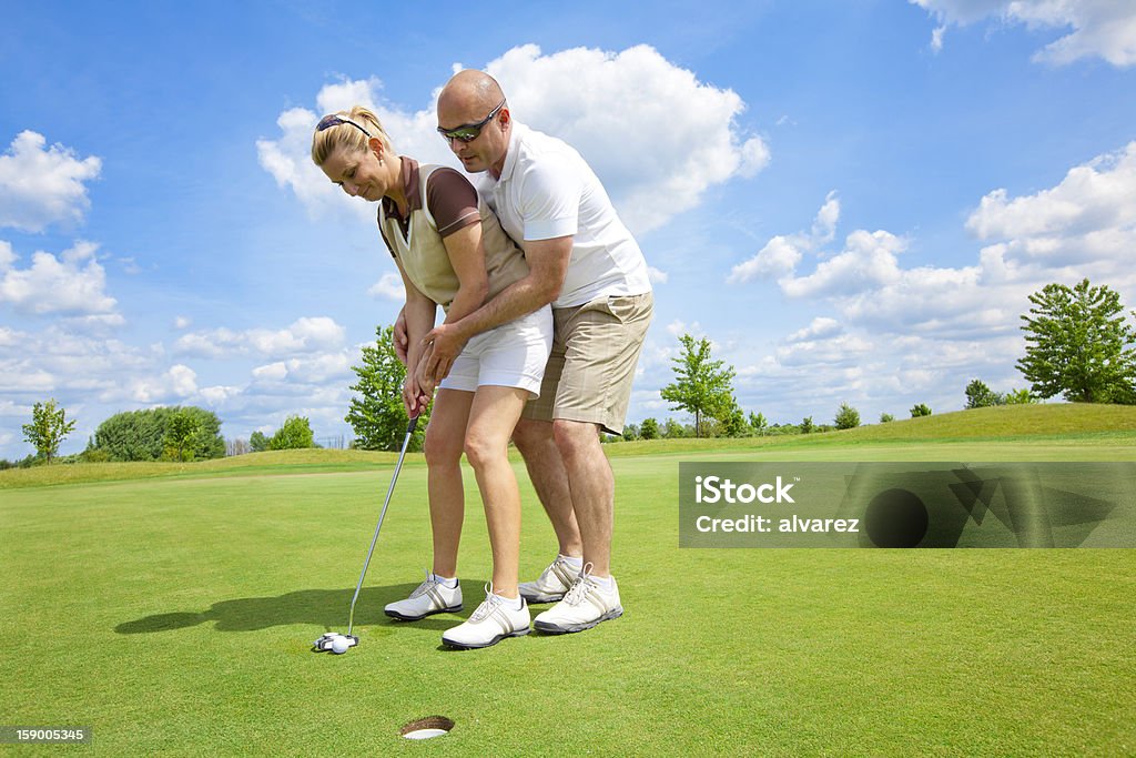 Uomo insegnando la sua moglie golf - Foto stock royalty-free di Esercizio fisico