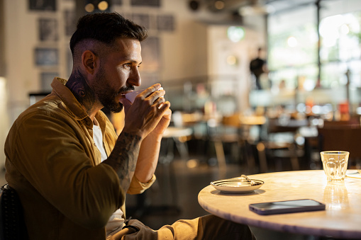 Hispanic man drinks coffee in a coffee shop
