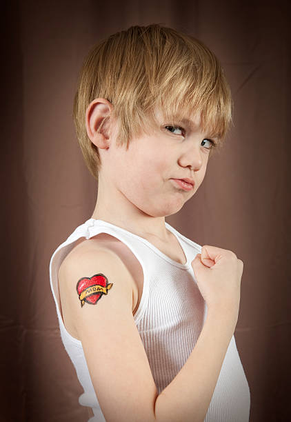 Tough Kid With Tattoo Kid with mom heart tattoo on his shoulder. tattoo arm stock pictures, royalty-free photos & images