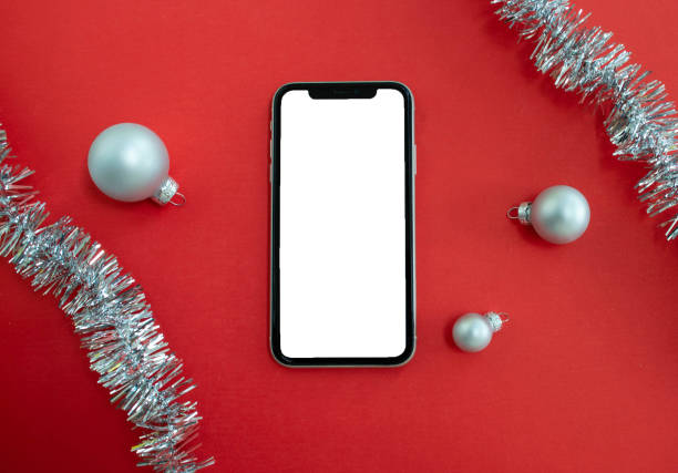 istock Mockup, smartphone, Christmas balls and tinsel on a red background. 1590068134