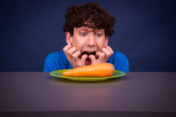 istock Funny silly guy eats carrots. Diet and healthy lifestyle. 1590079838