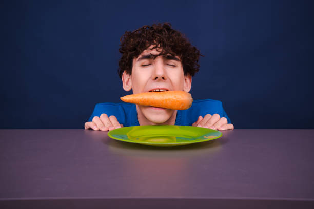 istock Funny silly guy eats carrots. Diet and healthy lifestyle. 1590094172