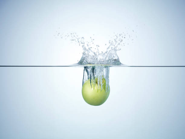 Fresh apple dropped in water. Apple splashing a lot of water droplets and bubbles you enter the water.