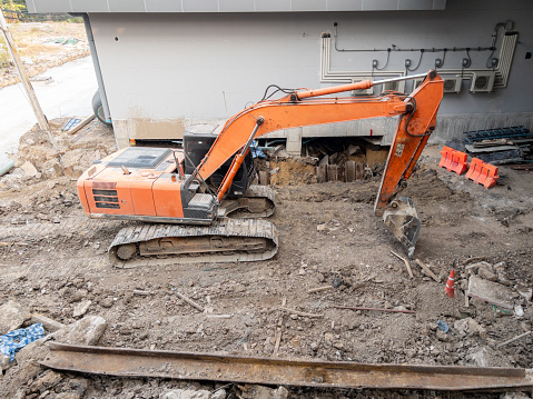 The large orange excavator in the site for construction of the monorail station in the city, front view for the copy space.
