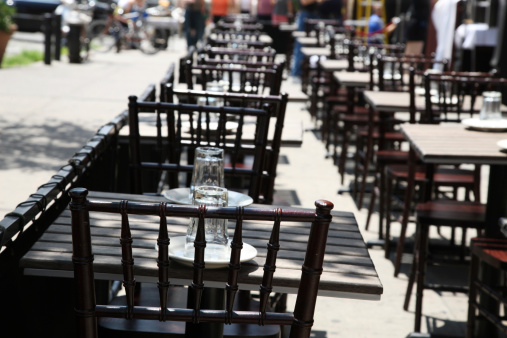 Line of tables at an outdoor restaurant with selective focus on first chair