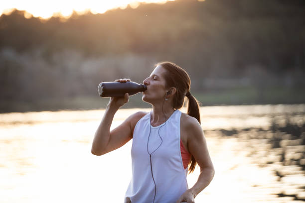 istock Woman drinking water from a bottle on the lake shore 1590101568