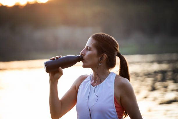 istock Woman drinking water from a bottle on the lake shore 1590101570