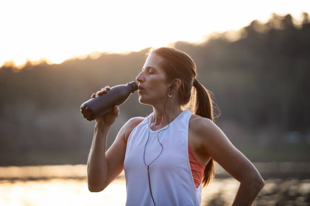 istock Woman drinking water from a bottle on the lake shore 1590102076