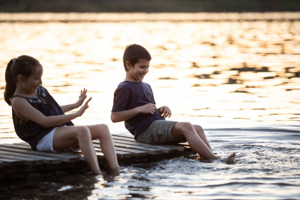 istock Two children playing on a lake dock 1590103652