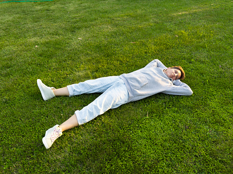Adult woman lying down on the grass. She lies happily on the grass in her own garden.