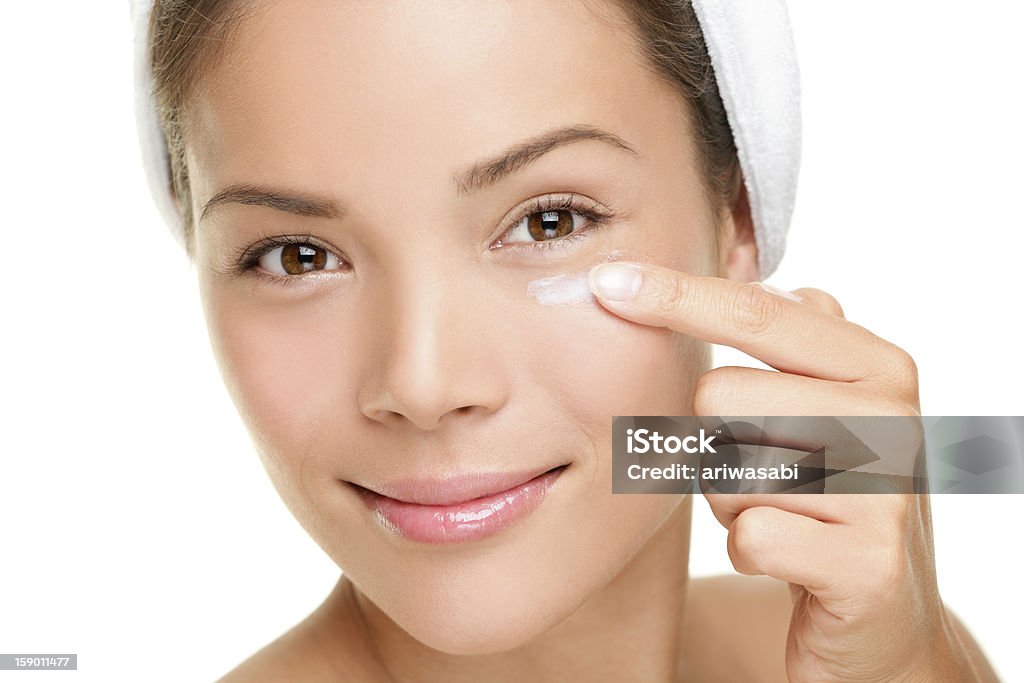 Face cream woman Face cream woman applying skin cream under eyes. Beauty eye contour cream, wrinkle cream or anti-aging skin care cream. Beautiful young mixed race Asian Chinese  beauty model in her 20s isolated on white background. Similar: Moisturizer Stock Photo