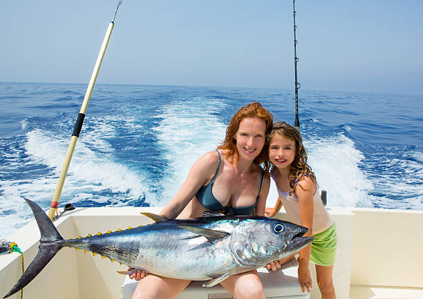 bikini fisher woman and daughter with bluefin tuna bikini fisher woman and daughter girl holding big bluefin tuna catch on boat deck freshwater fishing photos stock pictures, royalty-free photos & images