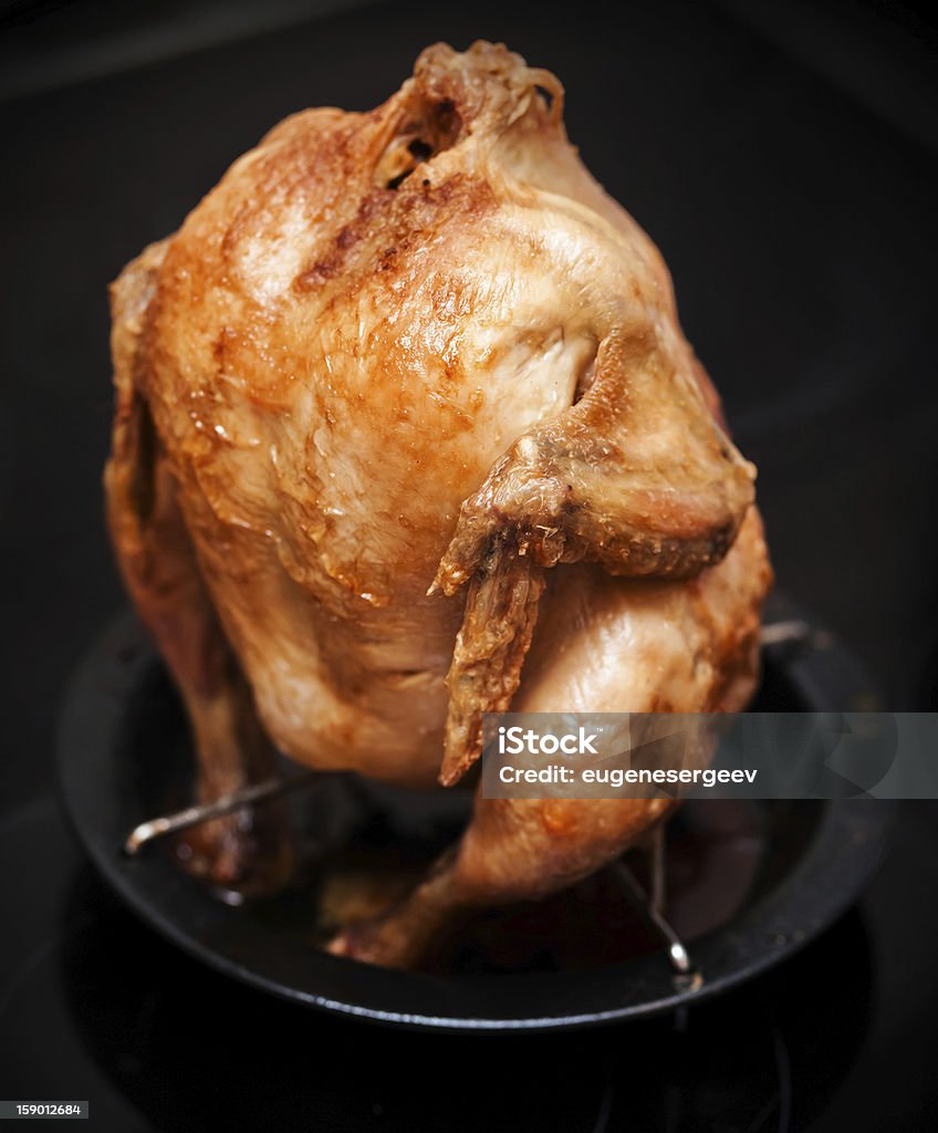 Whole grilled chicken on black metal pan Whole grilled chicken on black metal pan above dark background Baked Stock Photo