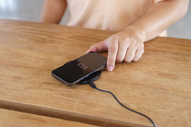 istock Charging mobile phone battery with wireless charging device in the table. Smartphone charging on a charging pad. Mobile phone near wireless charger Modern lifestyle technology concept. 1590137906