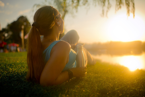 Woman enjoying sunset in a park near a river of lake
