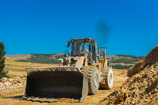 Backhoe collects stones in the quarry at work